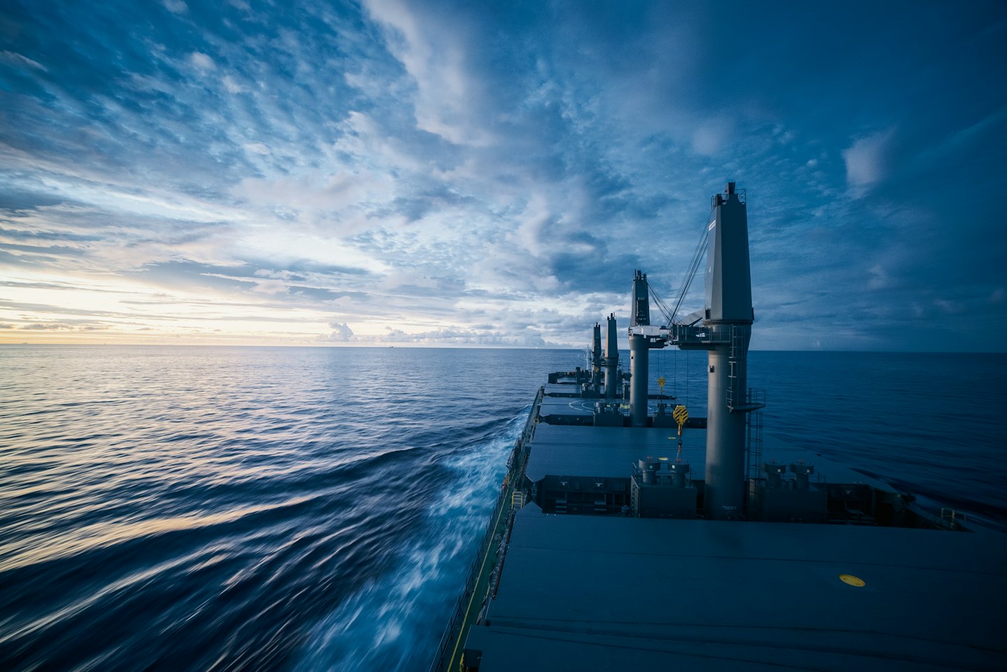 Large cargo ship sailing on the ocean at dusk.
