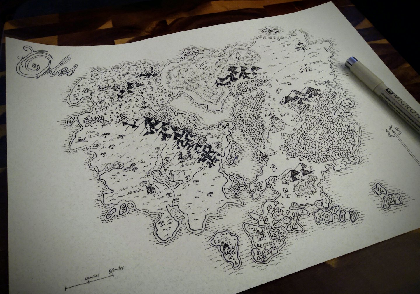 Hand-drawn fantasy map with a black pen on a wooden table.